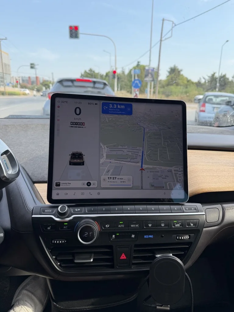 The iPad on the i3's dash above the climate controls, showing 0 km/h and the next turn in 3.3 km while the car waits at a red light